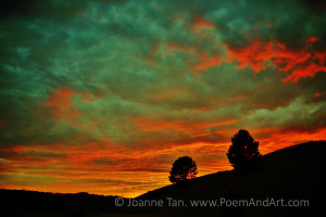 Sunset glories of yellow, orange, red, and green clouds over vanishing hills, photographed in Northern California.