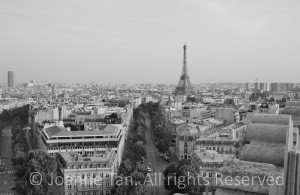 Eiffel Tower in the city scape of buildings and towers, boulevards lined with trees.