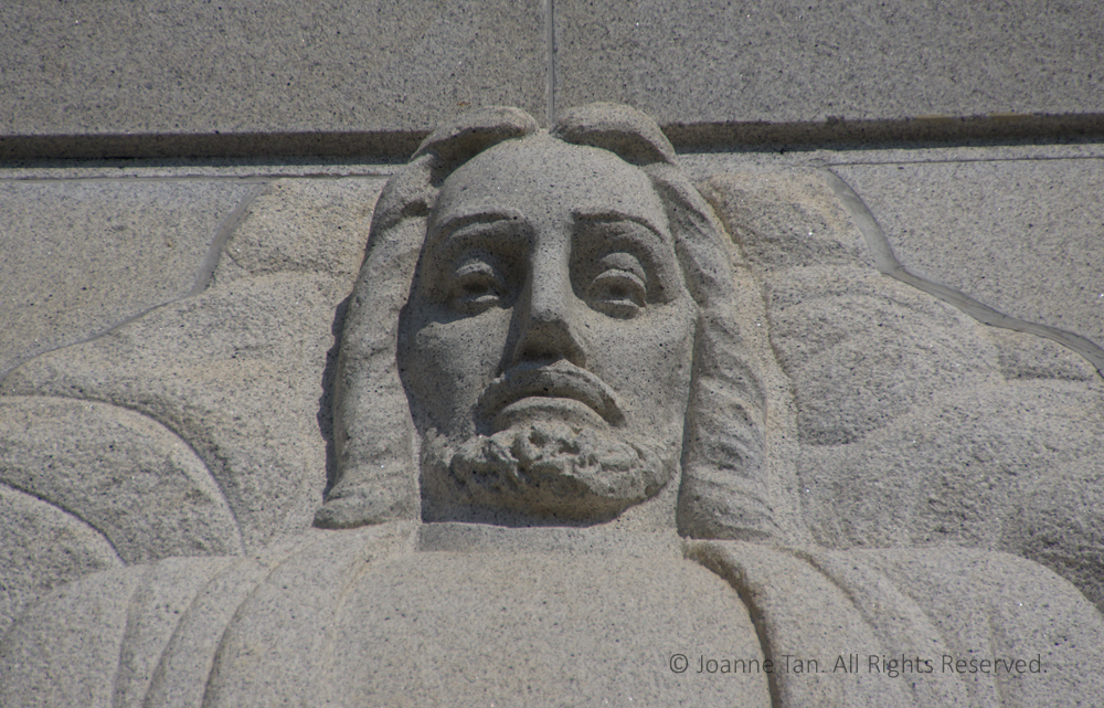 The face of Christ looking down carved on granite exterior top wall of the Mormon Temple in Oakland, California.